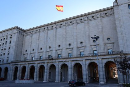 Edifício histórico da administração pública em Madrid, com a bandeira da Espanha no topo.