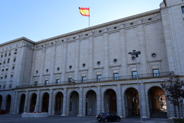 Edifício histórico da administração pública em Madrid, com a bandeira da Espanha no topo.