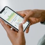 Mãos seguram um smartphone que exibe um aplicativo de monitoramento da saúde com gráficos e dados.