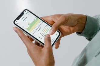 Mãos seguram um smartphone que exibe um aplicativo de monitoramento da saúde com gráficos e dados.
