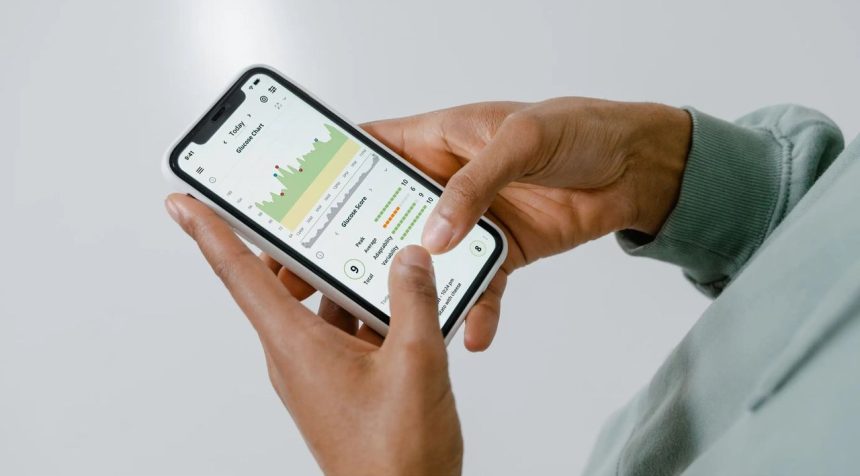 Mãos seguram um smartphone que exibe um aplicativo de monitoramento da saúde com gráficos e dados.