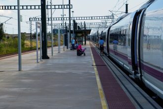 Passageiros aguardam na plataforma ao lado de um trem de alta velocidade em uma estação ferroviária de Barcelona.