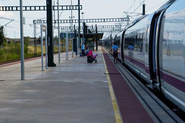 Passageiros aguardam na plataforma ao lado de um trem de alta velocidade em uma estação ferroviária de Barcelona.