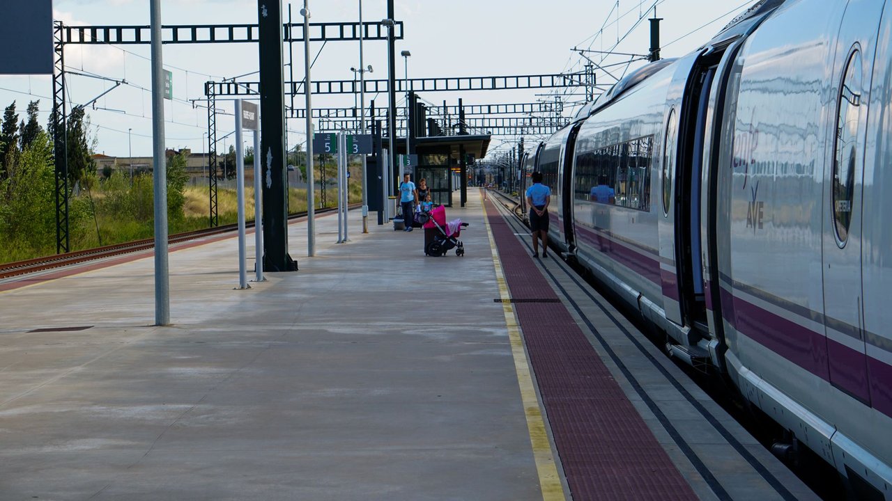Passageiros aguardam na plataforma ao lado de um trem de alta velocidade em uma estação ferroviária de Barcelona.