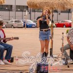 Músicos se apresentam ao vivo com violão, cajón e vocais diante do público.