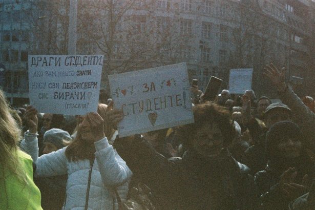 Grupo de estudantes participa de um protesto ao ar livre segurando cartazes.