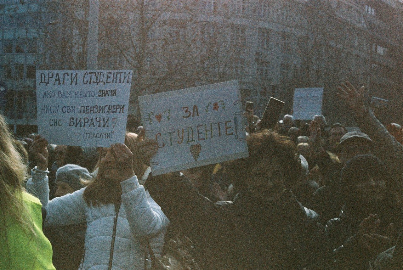 Grupo de estudantes participa de um protesto ao ar livre segurando cartazes.