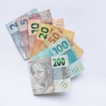 Cédulas de reais brasileiros dispostas em leque sobre fundo branco.